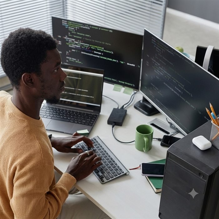 Developer working across multiple monitors on a client project